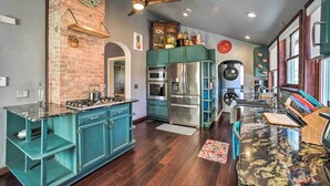 A kitchen with teal cabinetry, stainless steel appliances, and a marble countertop. - Historic Old Colorado City Home w/ Backyard! (Colorado Springs)
