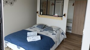 Ein ordentlich bezogenes Bett mit einer blauen und weißen Bettdecke, ein Paar weiße Handtücher und ein Spiegel über dem Bett.