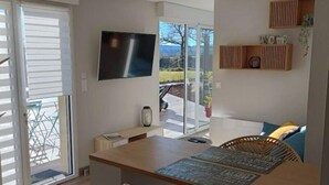 Eine moderne Küche mit einer zentralen Kochinsel, Barhocker, einem Flachbildfernseher und einer Glastür zu einem Außenbereich.