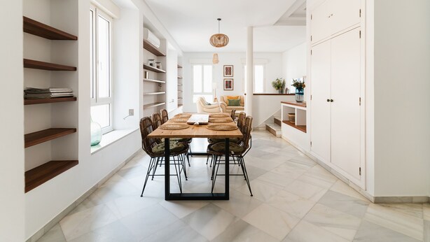 A modern dining area with a wooden table and chairs, white walls, and built-in shelving. - Real Carretería. 3 bedrooms, 3 bathrooms, terrace, views (Sevilla)