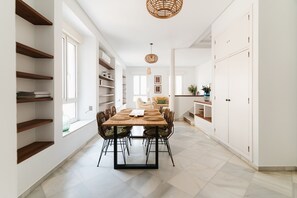 A modern dining area with a wooden table and chairs, white walls, and built-in shelving. - Real Carretería. 3 bedrooms, 3 bathrooms, terrace, views (Sevilla)