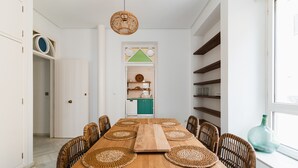 A dining area with a wooden table, woven placemats, wicker chairs, and a view of a kitchen through an open door. - Real Carretería. 3 bedrooms, 3 bathrooms, terrace, views (Sevilla)