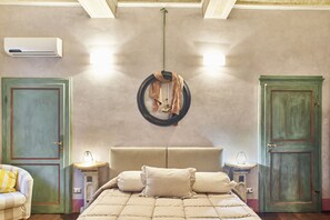 Un dormitorio con una cama grande, dos mesitas de noche, una lámpara colgante y una puerta verde.
