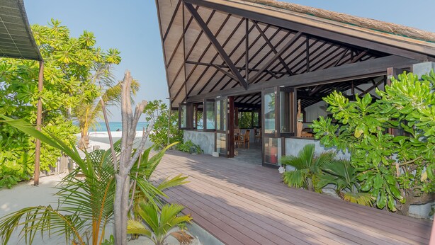 A beachside resort with a wooden deck, outdoor seating, and tropical plants. - Premier Beach (Gulhi)