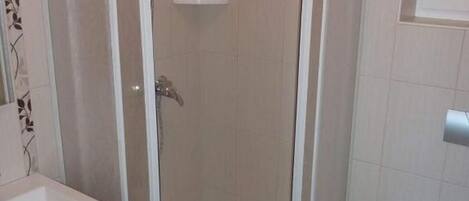 A corner bathroom with a glass-enclosed shower, a toilet, and a sink.