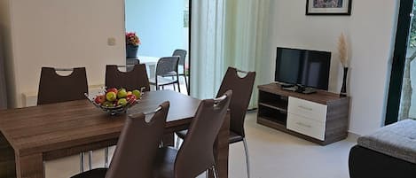 Ett modernt vardagsrum med en matplats, en tv och en klocka på väggen.