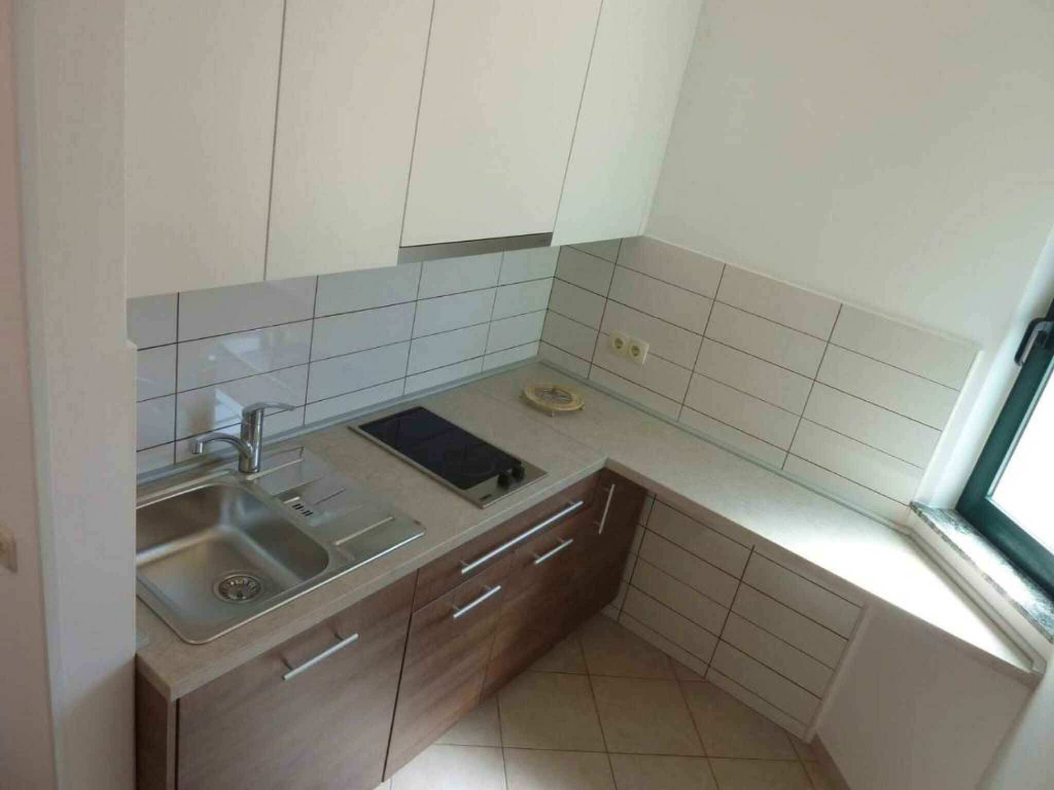 A compact kitchen with a sink, stove, and wooden cabinets.
