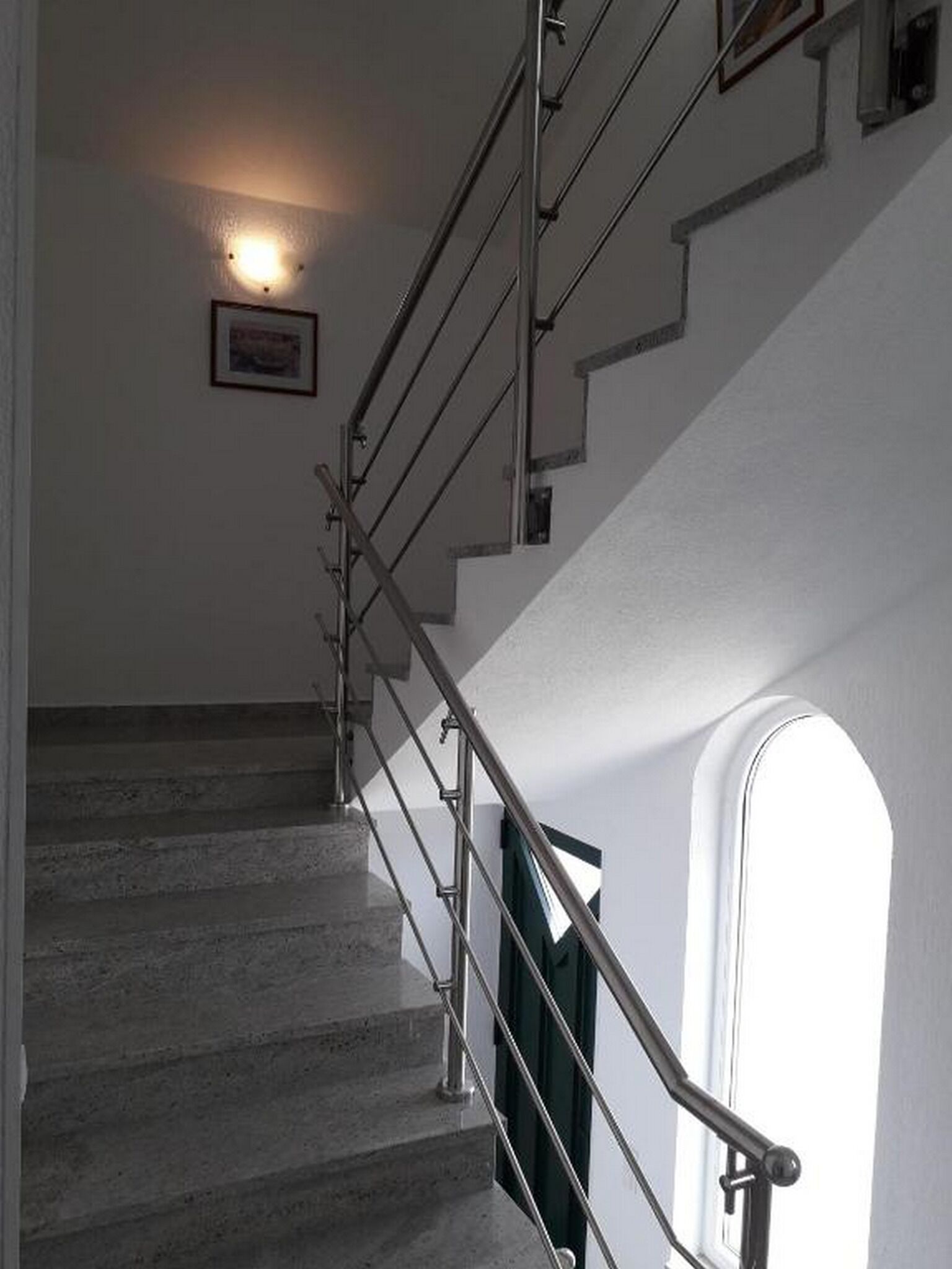 A staircase with metal railings and a light fixture on the wall.