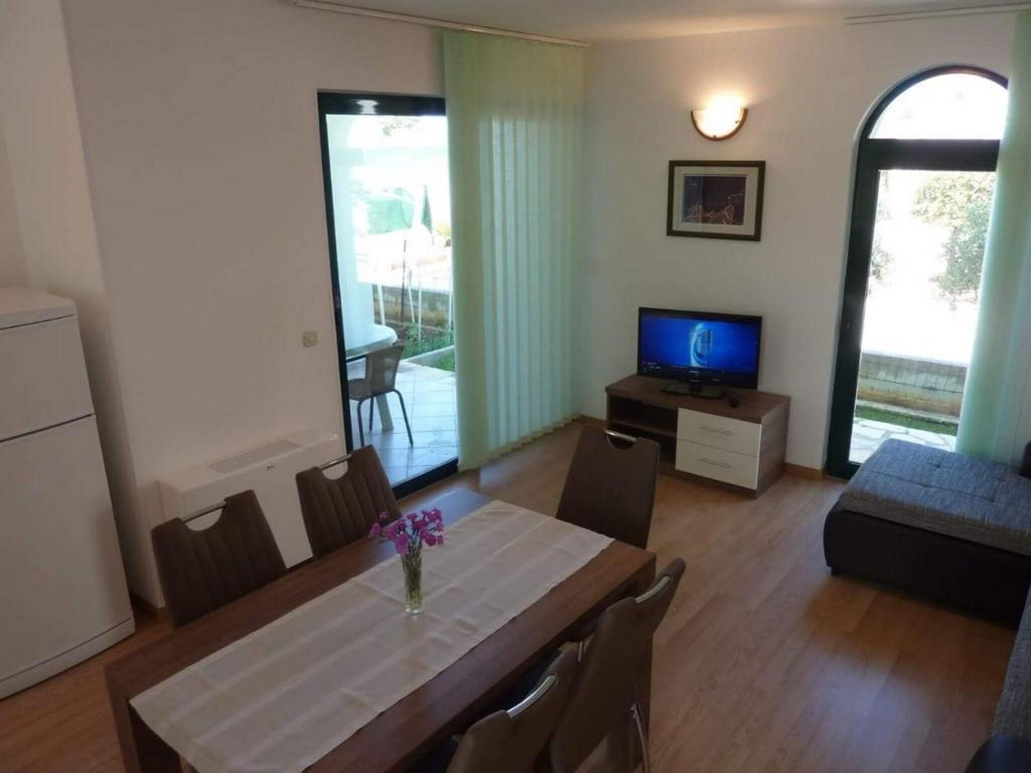 A compact living space with a dining area, a television, and a sofa.