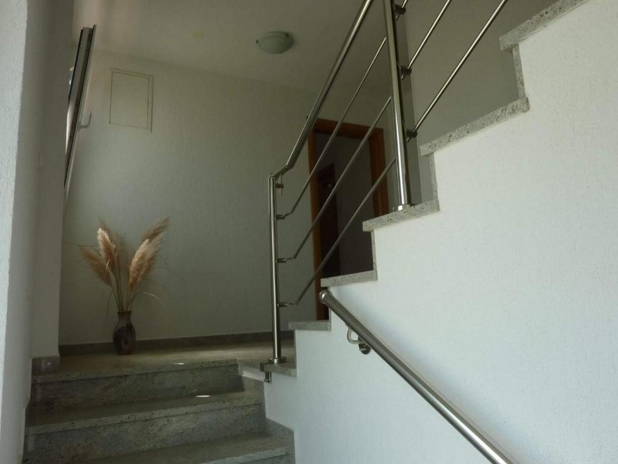 Eine Treppe mit Metallgeländern und einer Vase mit Pampasgras.