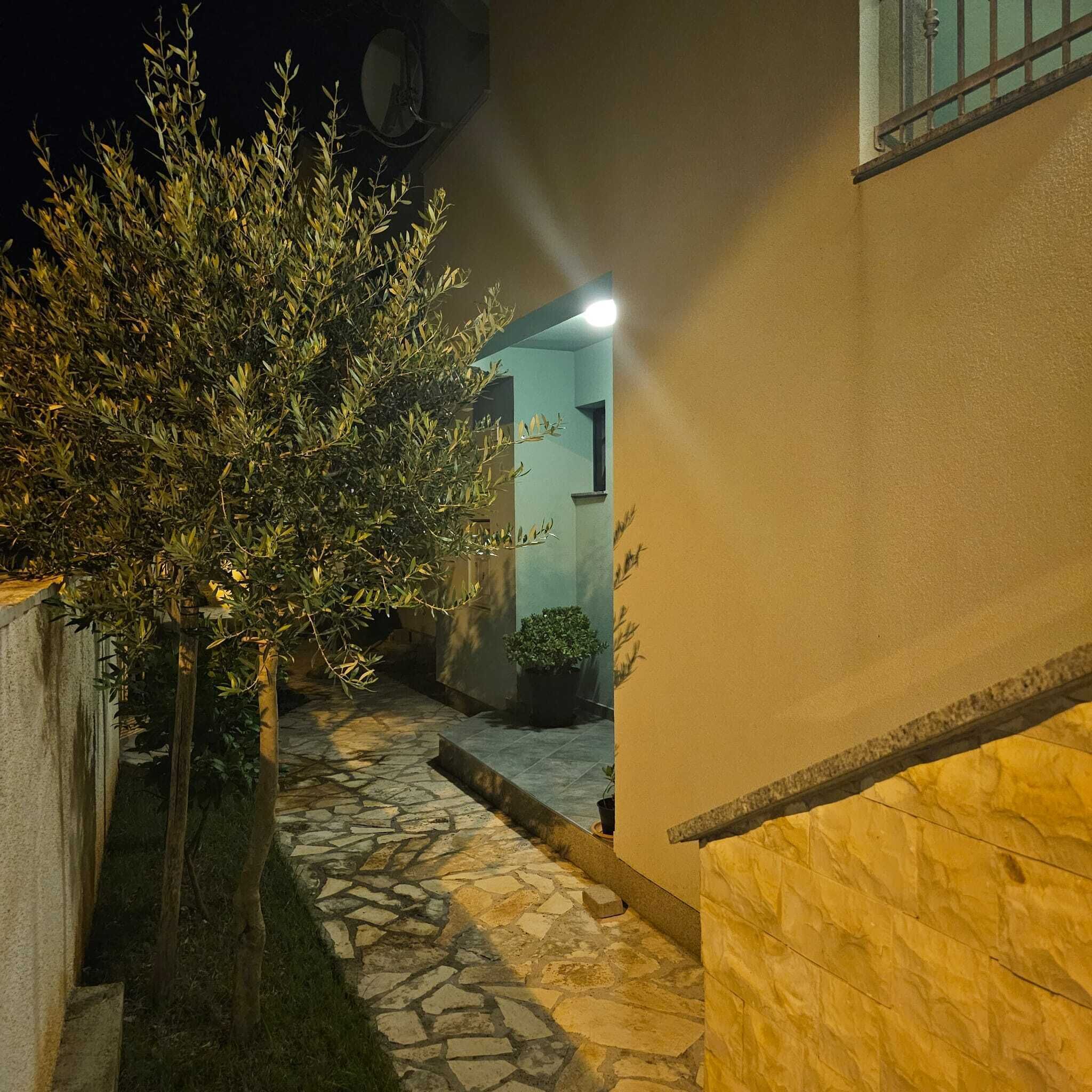 Un sendero de piedra que conduce a un edificio con una fuente de luz iluminando la entrada.