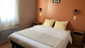 Ein Schlafzimmer mit einem Bett, zwei Nachttischen, einem Fenster mit Vorhängen und einem Wandbild.