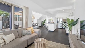 Een moderne woonkamer met een bank, een salontafel, en uitzicht op de keuken en eetruimte.