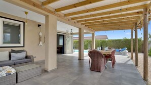 A covered outdoor area with a pool, a dining table, and wicker furniture. - Villa Kas Gia with garden and lovely private pool (Kralendijk)