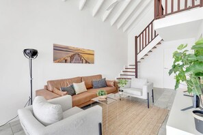 Un salon moderne comprenant un canapé, un fauteuil, une table basse et un escalier.