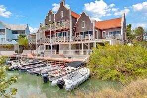 Une propriété située au bord de l’eau, comprenant un immeuble à plusieurs étages, un quai avec des bateaux et un paysage verdoyant luxuriant.