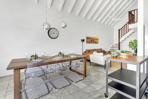 Un espace de vie moderne comprenant un coin repas, un canapé, un escalier et un ventilateur de plafond.