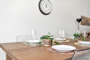A dining table set with plates, glasses, and a clock on the wall.