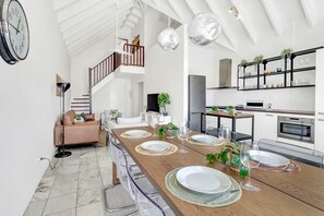 A spacious living area with a dining table set for four, a kitchen with modern appliances, and a staircase leading to an upper floor. - Caribbean Court Apartment Djodjo, marina views (Kralendijk)