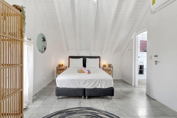 Une chambre avec un grand lit, des tables de chevet, un miroir et une vue sur la salle de bain.