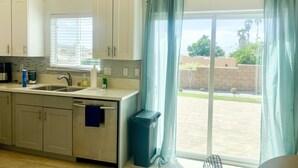 Una cocina moderna con armarios blancos, un lavamanos de acero inoxidable y una ventana con persianas.