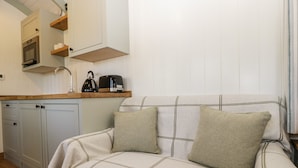 A cozy kitchenette with a built-in oven, a coffee maker, and a kettle on a wooden countertop.