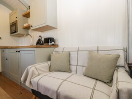 Una kitchenette acogedora con horno empotrado, cafetera y hervidor sobre una encimera de madera.