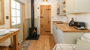 A compact kitchen with a wood-burning stove, a sink, and a toaster.