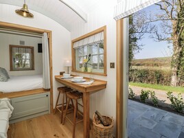 Una habitaci ón acogedora con una cama, una mesita con taburetes, una ventana con cortinas y vistas al exterior.