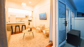 A modern kitchen with a microwave, refrigerator, and bar stools. There is a dining area with a round table and chairs. - Refurbished Villa  ✨ NEW ✨ Hot tub, Netflix, & Entirely private (Hastings)