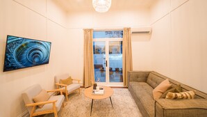 A modern living room with a large TV, comfortable seating, a coffee table, and a view through a glass door to the outside. - Refurbished Villa  ✨ NEW ✨ Hot tub, Netflix, & Entirely private (Hastings)