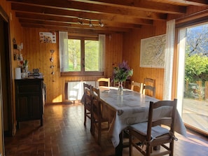 Enjoy meals in this warm dining area with a round table, vase with flowers, and comfortable seating.
