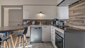 A modern kitchen with wooden beams, a built-in dishwasher, a coffee maker, and a refrigerator. - Charming Farmhouse Retreat with Enclosed Garden, A/C, and Farm Tours in Berry (Cluis)