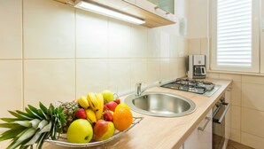 A kitchen with a fruit bowl on the counter, a sink, and a stove. - Apartment Marina Obod (Konavle)
