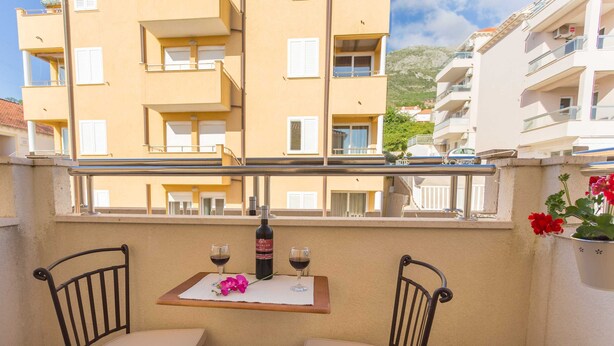 A balcony with two chairs, a table, and a bottle of wine. - Apartment Marina Obod (Konavle)
