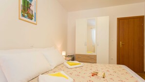 A hotel room with a bed, a mirror, a wooden door, and a nightstand with a lamp. - Apartment Marina Obod (Konavle)