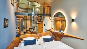 Een moderne slaapkamer met een houten hoofdeinde, een gebogen trap en een grote spiegel.