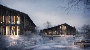 Een besneeuwd landschap met twee houten gebouwen, waarvan er een grote ramen en een schuin dak heeft, en de ander een vergelijkbaar ontwerp.