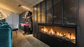 Een moderne woonkamer met een open haard, een comfortabele smaragdgroene bank en een decoratieve metalen sculptuur.