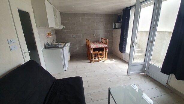 A compact living space with a kitchenette, a dining area, and a glass door leading to an outdoor area. - Rental T1 30m2 with Terrace in Brem Sur Mer: 2km from the beach (Brem-sur-Mer)