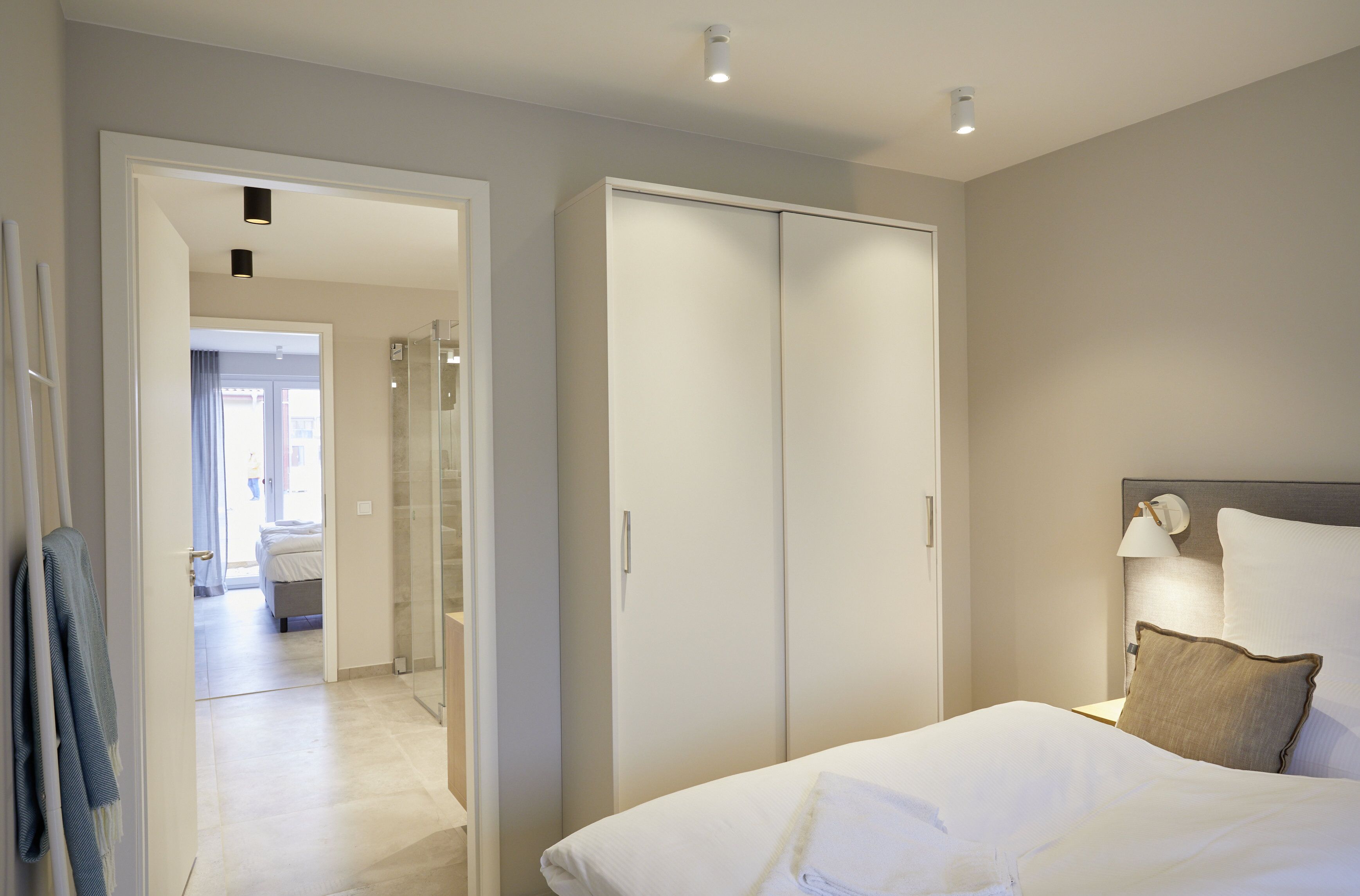 A hotel room with a bed, a wardrobe, and a bathroom visible through an open door.
