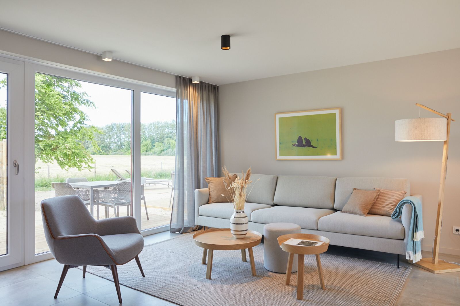 A modern living room with a sofa, armchair, coffee table, and a lamp.