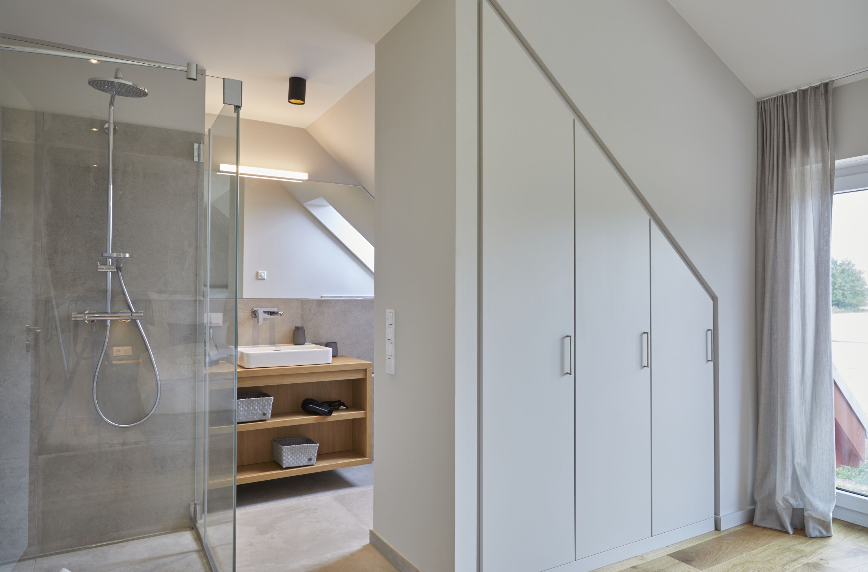 Une salle de bain moderne avec une douche à parois de verre, un meuble-lavabo en bois et une grande armoire.