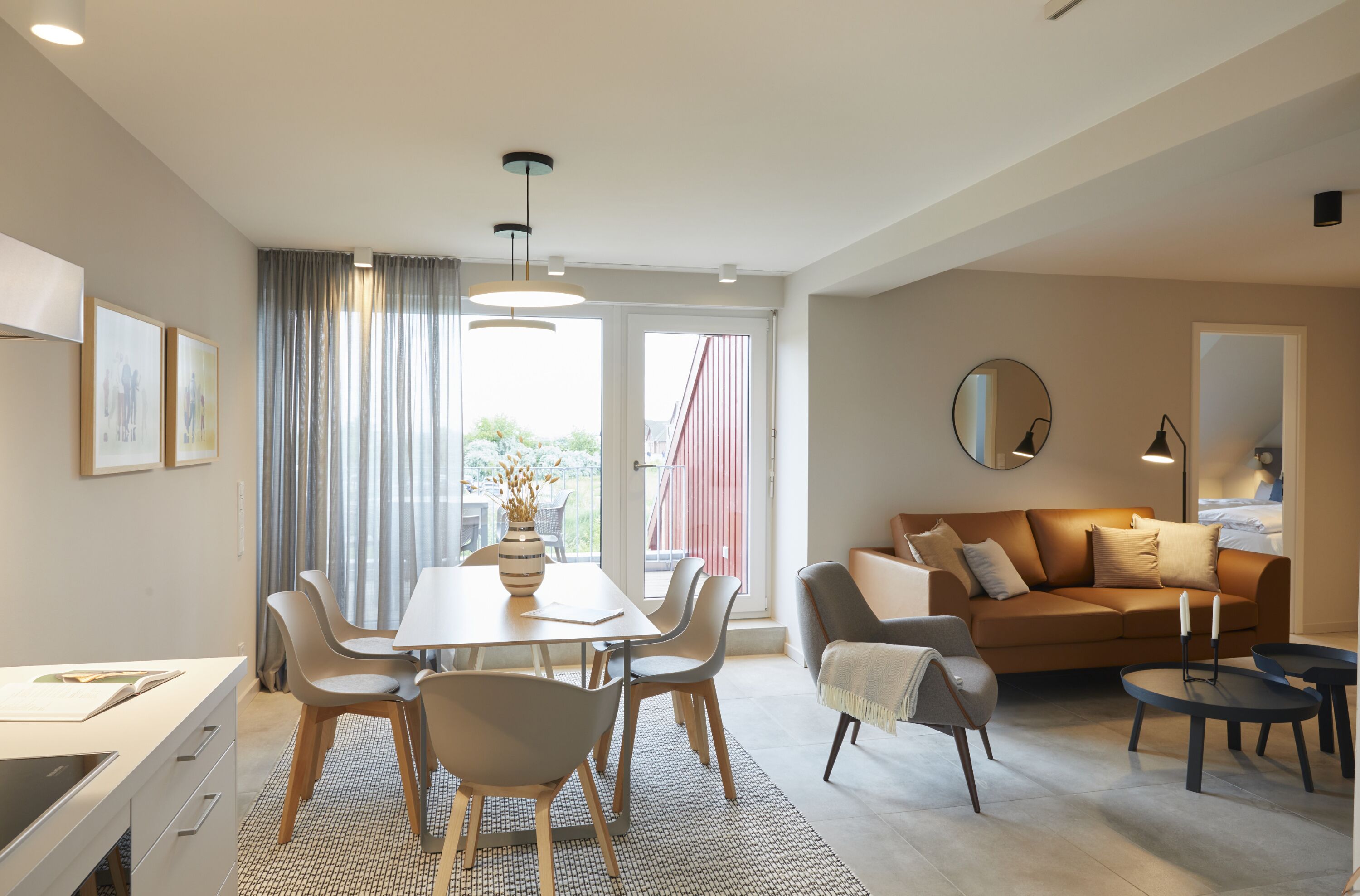 A modern living room with a sofa, a dining table with chairs, a coffee table, and a large window with curtains.