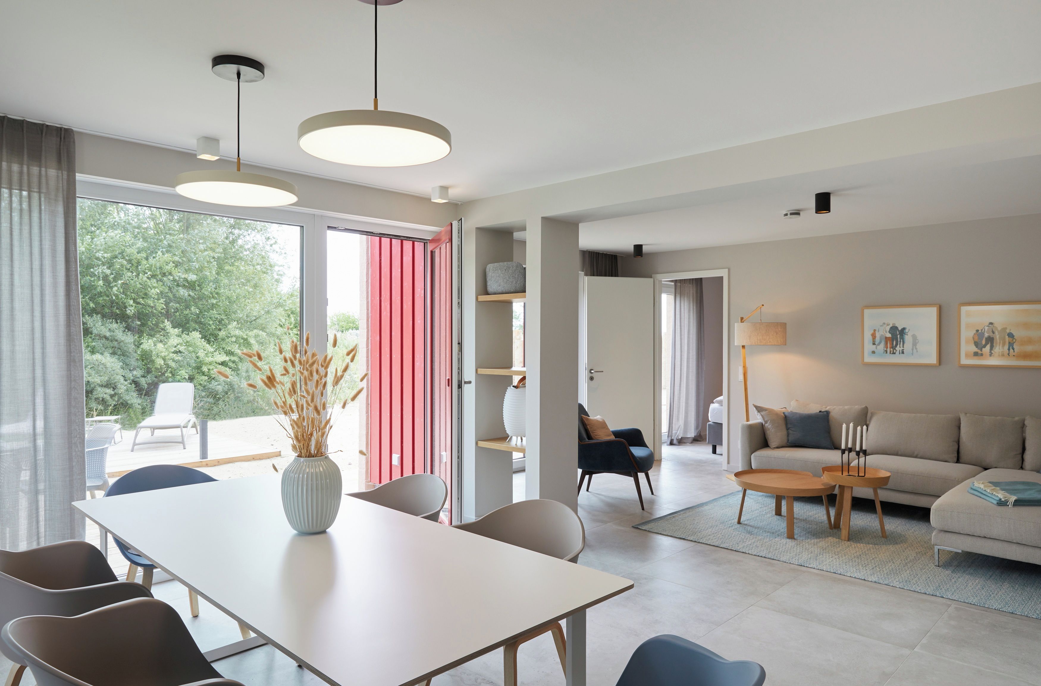 A modern living room with a sofa, coffee table, and dining area with chairs.