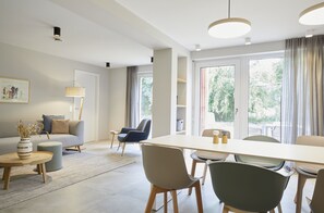 Una sala moderna con un sofá, una mesa de comedor con sillas, una mesa de centro y una lámpara.