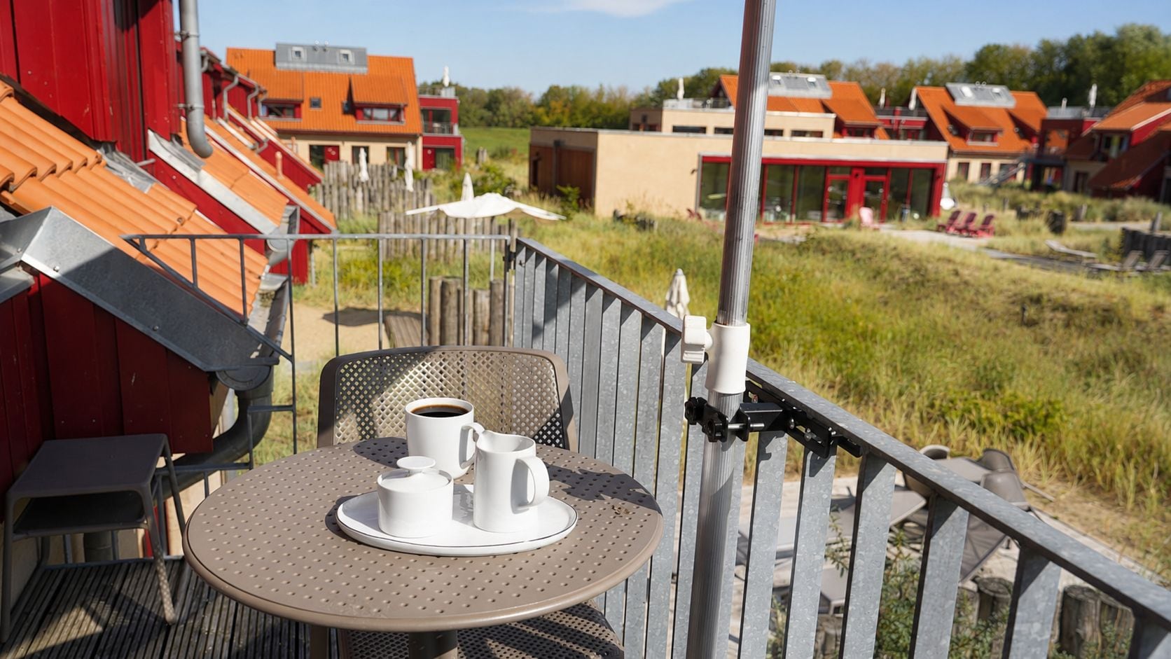 A balcony with a table set for two, a chair, and a railing.