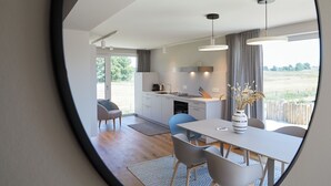 Eine moderne Küche mit Essbereich, großen Fenstern und Blick ins Freie.