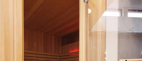 A sauna room with wooden benches and a glass door.