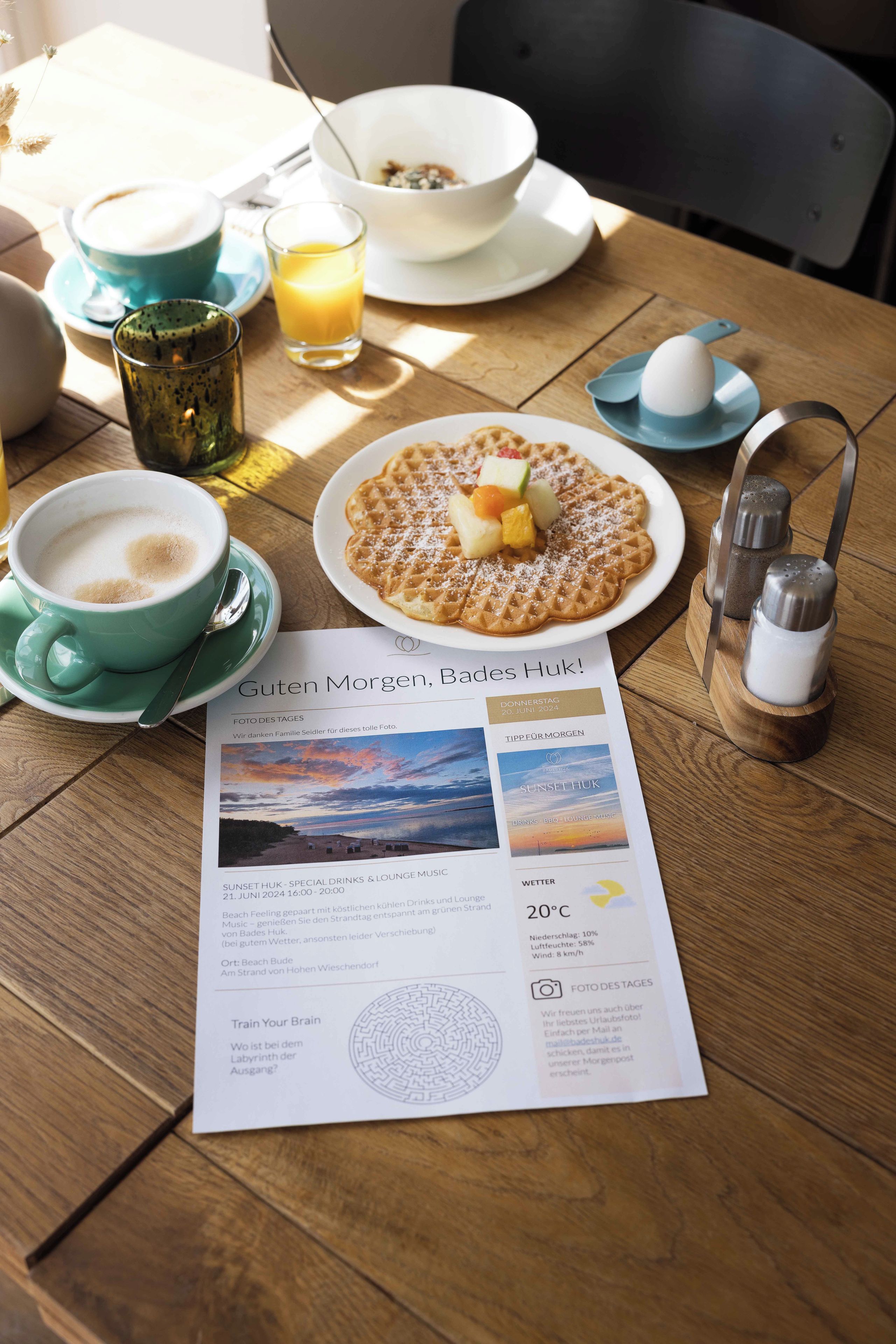 Een ontbijtje met een wafel, fruit en koffie op een houten tafel.